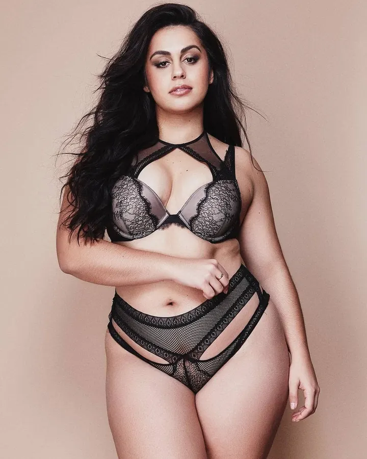 Femme aux cheveux bruns-noirs, seins nus, allongée sur un lit, regardant vers le bas