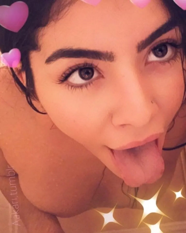 Femme aux cheveux noirs, regard intense, prenant un selfie dans un miroir, visage partiellement visible