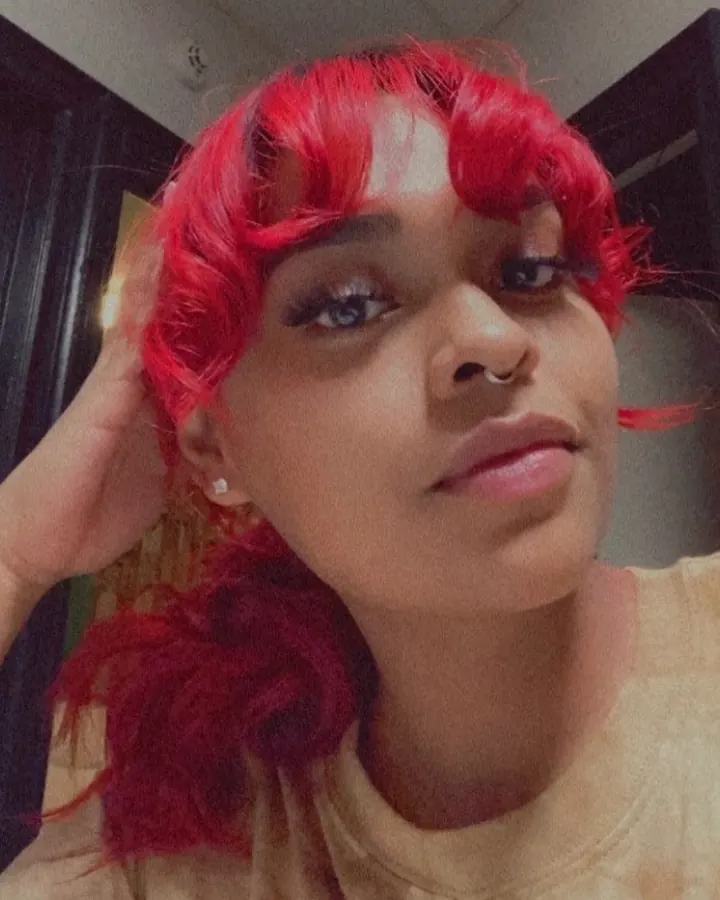 Femme aux cheveux roux, regard intense, prenant un selfie dans un miroir, visage partiellement visible