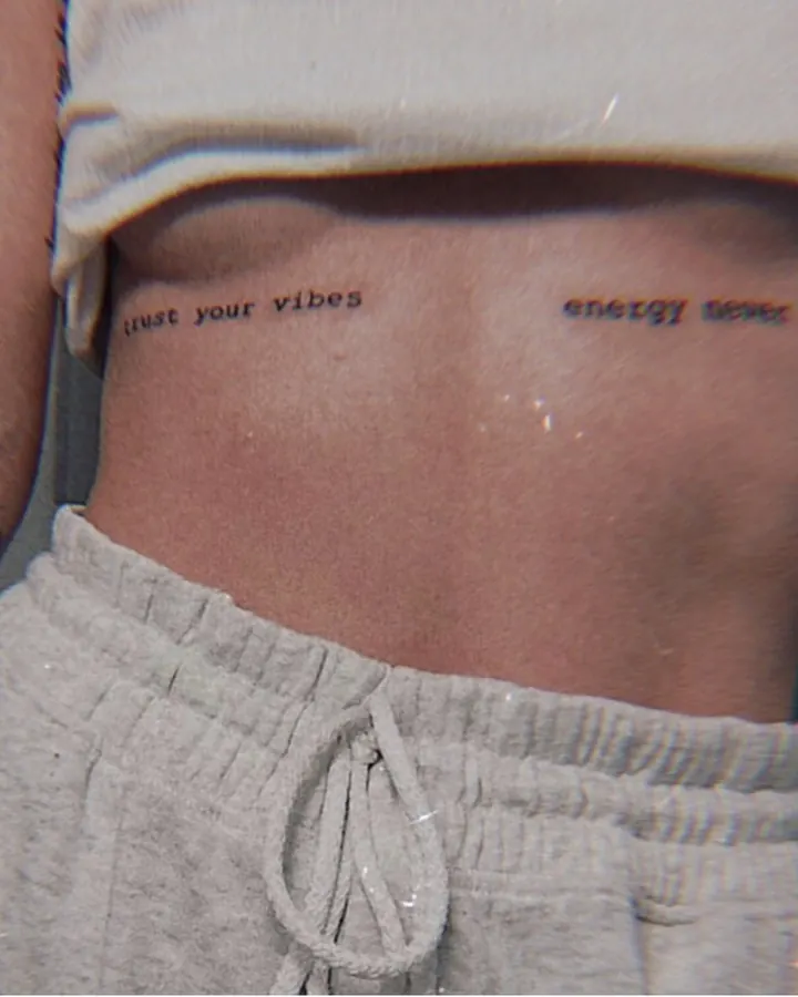 Femme aux cheveux bruns-noirs prenant un selfie dans un miroir, en haut blanc et culotte blanche, dans une pièce intérieure.